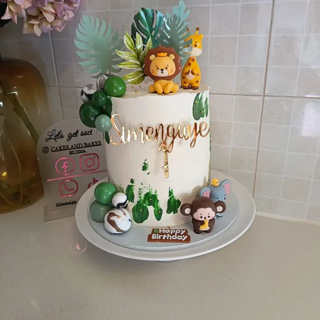 Safari birthday cake with hand-modelled lion, giraffe, monkey, and elephant figures